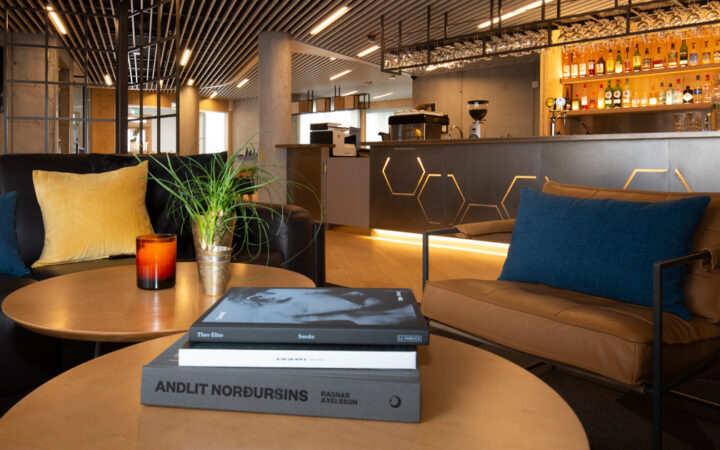 Lounge & bar at Landhotel in South Iceland with modern aesthetic of steel & wood, with stuffed chairs of leather, blue & gold.