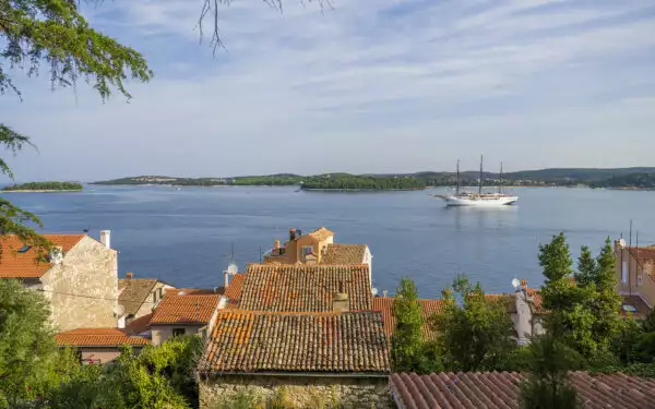 The luxury Mediterranean cruise yacht Sea Cloud: Lindblad, a historic windjammer style & white-painted wooden hull navigates off shore in Croatia.