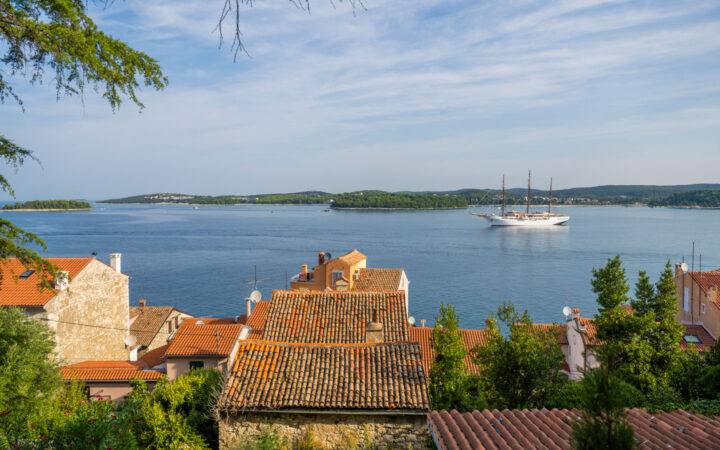 The luxury Mediterranean cruise yacht Sea Cloud II: Lindblad, a historic windjammer style & white-painted wooden hull navigates off shore in Croatia.