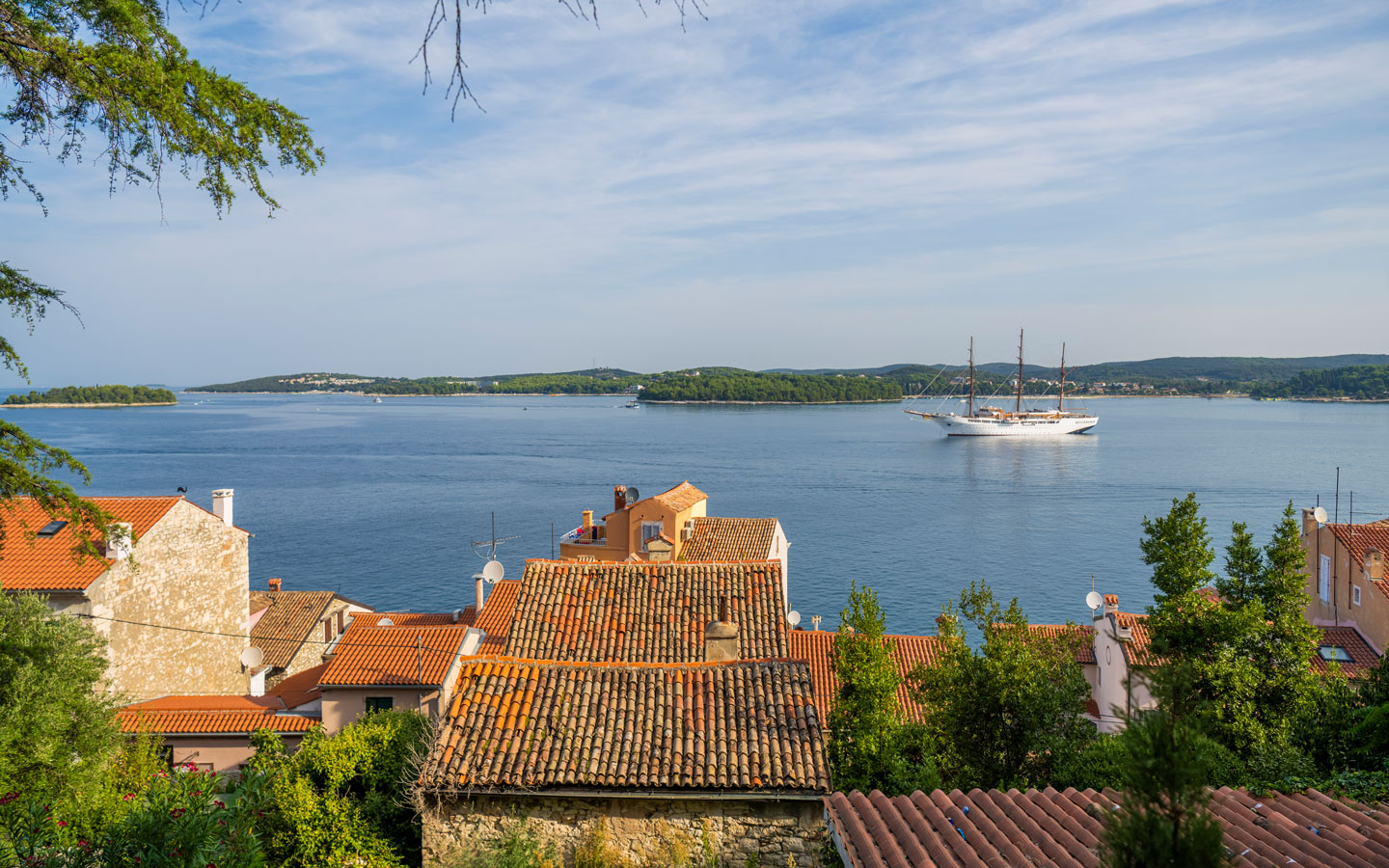The luxury Mediterranean cruise yacht Sea Cloud II: Lindblad, a historic windjammer style & white-painted wooden hull navigates off shore in Croatia.