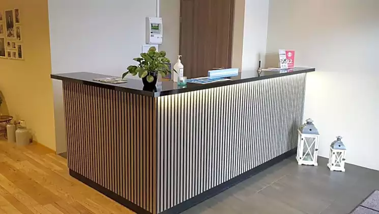 Empty reception desk in dark & light slatted wood in white-walled lobby of Milk Factory hotel in south Iceland.