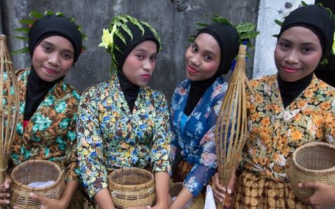 Women dressed in traditional clothing hold spice baskets in indonesia
