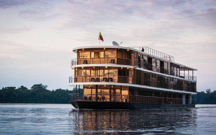 Anakonda small ship with 4 guest decks including open-air trop deck, in copper color, cruising the River.