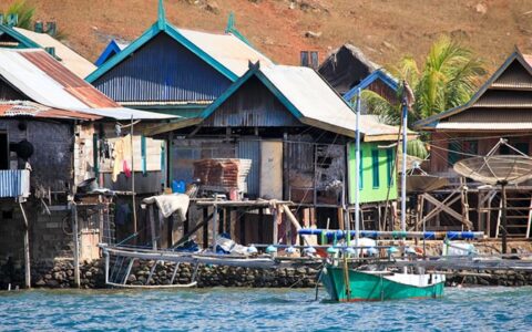 A fishing village with basic wooden homes built on stilts over the blue waters of Indonesia, visited during the Aqua Blu Indonesia cruise between Bali & Flores, to Komodo National Park.