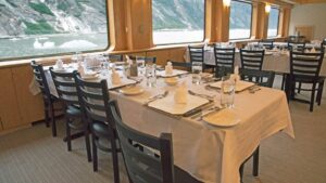 Dining room with several tables by the windows aboard Chichagof Dream