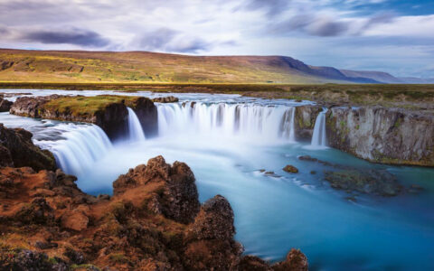 Massive Godafoss waterfall with grassy plateau dropping into turquoise pools, seen on A Circumnavigation of Iceland cruise.