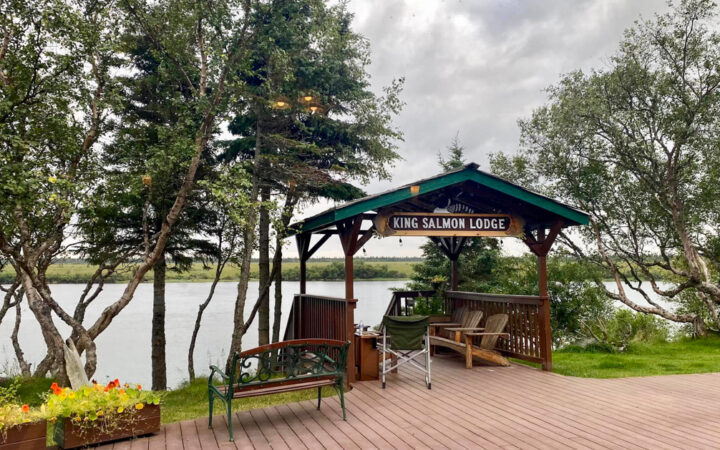Outdoor patio of king salmon lodge with outdoor seating under wooden canopy looking over the water on a cloudy day