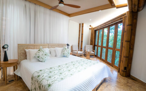 A large superior stateroom at La Selva Ecolodge with a king bed a large bay of windows looking out to the jungle in Ecuador