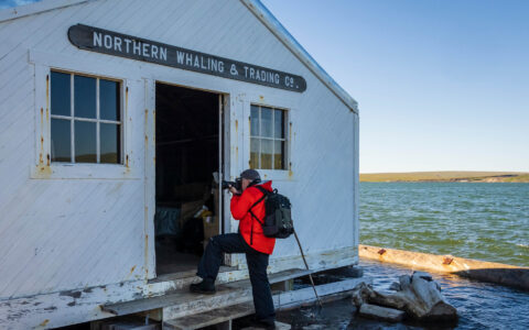 Traveler photographs a historic whaling building on Herschel Island during an Arctic expedition cruise.