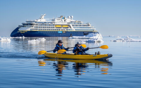 Kayakers paddle near a National Geographic Endurance in icy Svalbard waters.