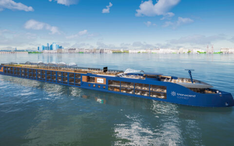 Modern blue riverboat National Geographic Connect with open-air teak top deck sits in calm sea on a sunny day in Europe.