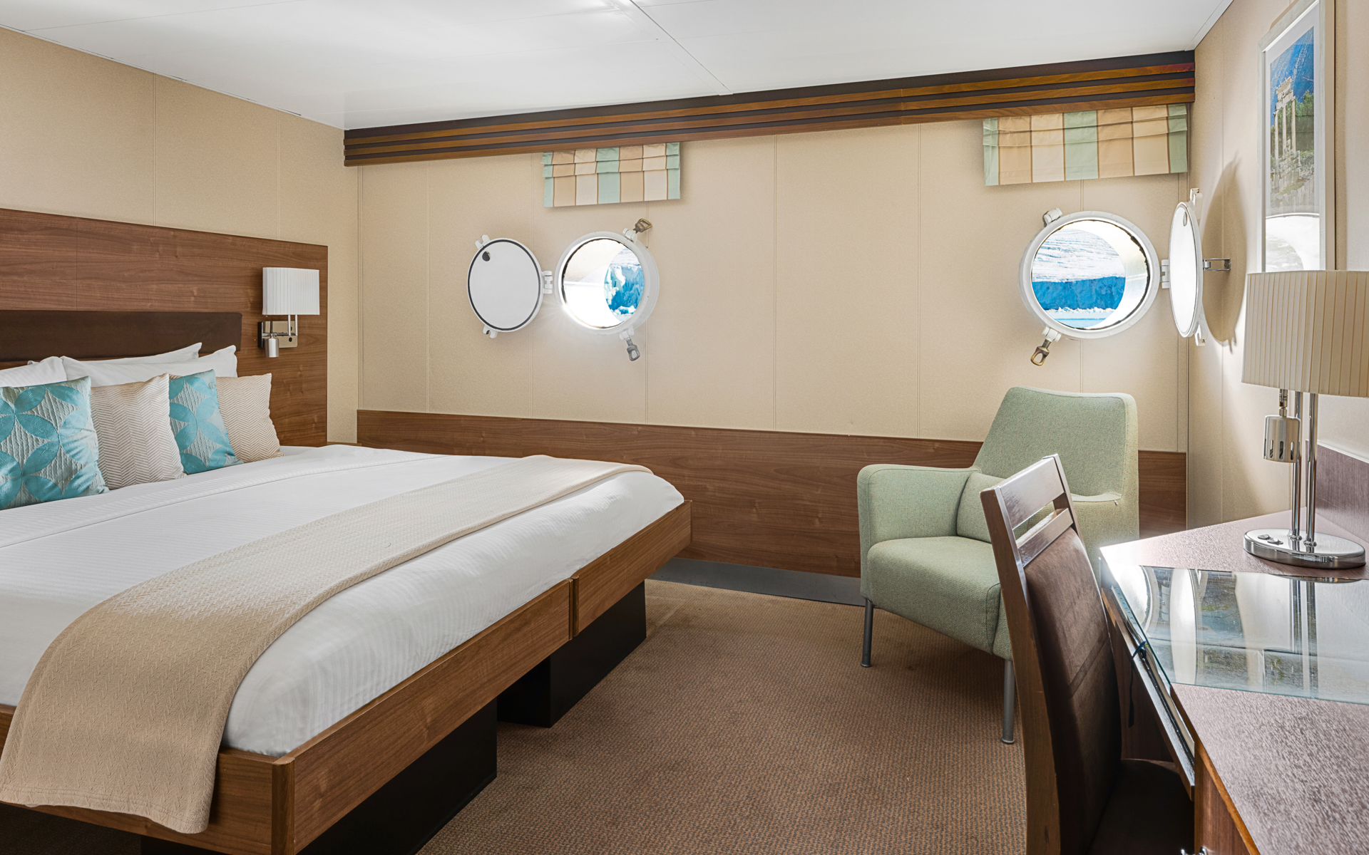 A large double bed and portholes are featured in this category 1 cabin with warm wood aboard the National Geographic Explorer