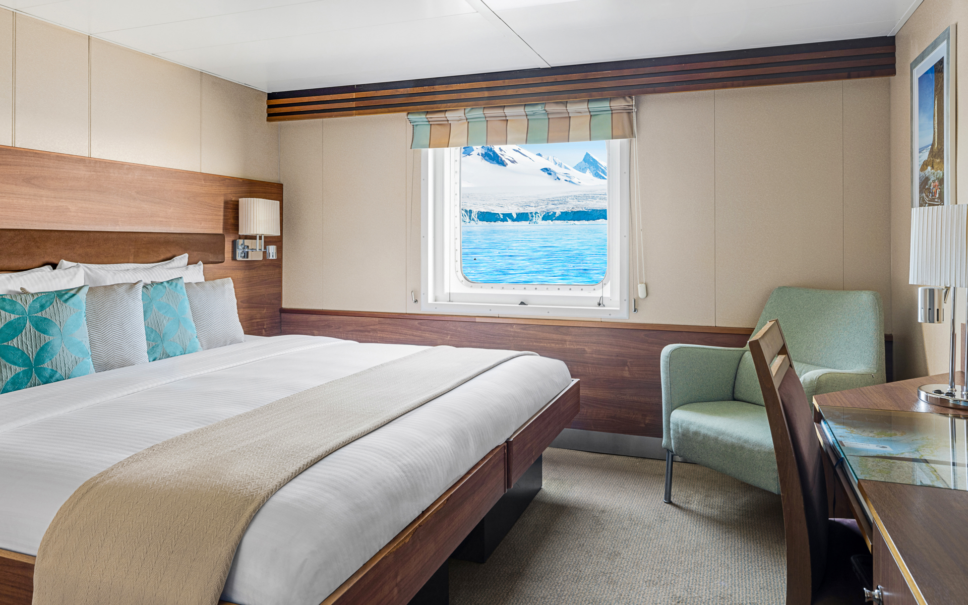 A large double bed and window are featured in this category 2 cabin with warm wood aboard the National Geographic Explorer