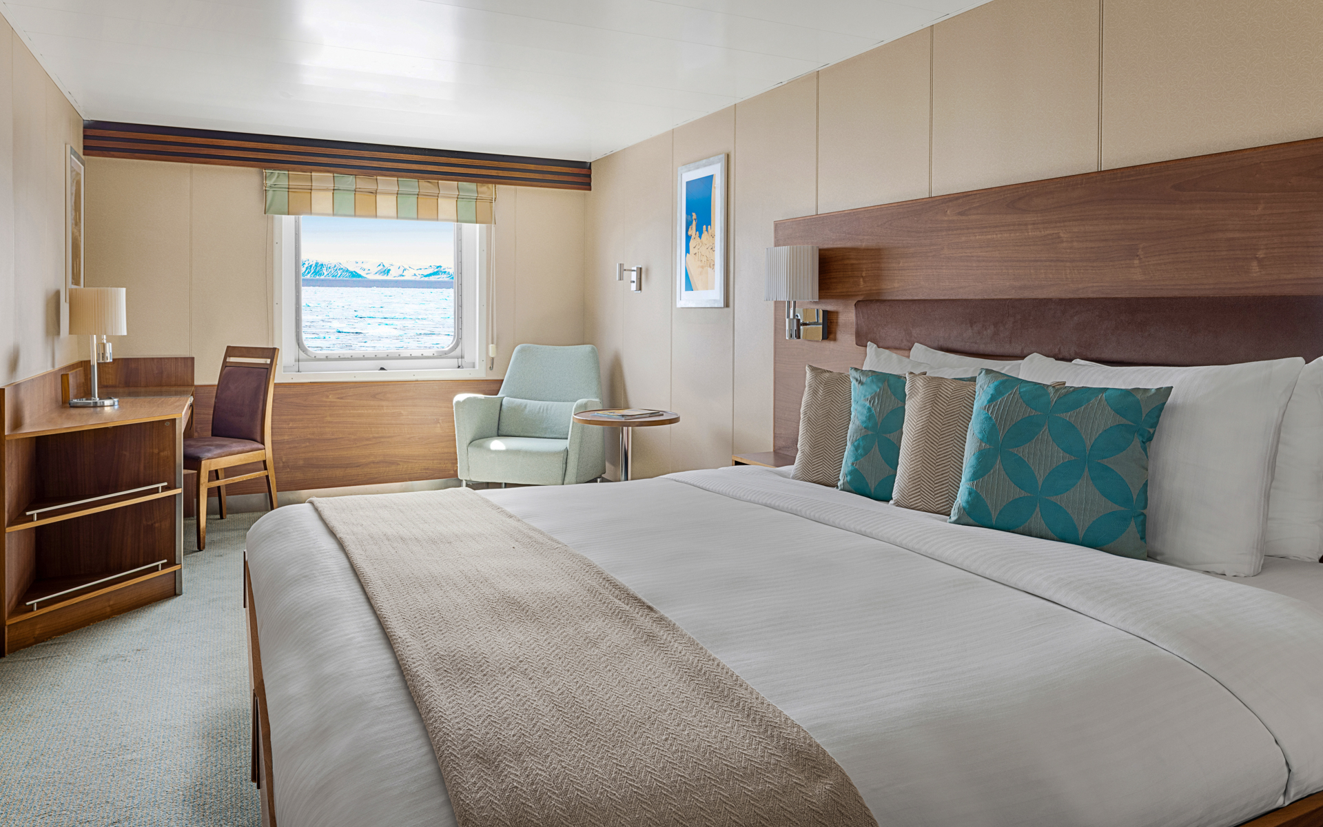 A large double bed and window are featured in this category 3 cabin with warm wood aboard the National Geographic Explorer