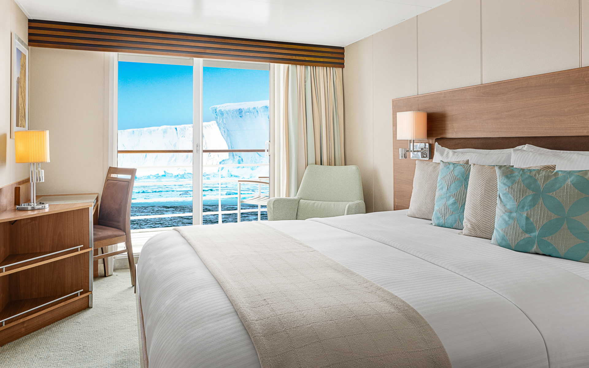 A large double bed and balcony are featured in this category 5 cabin with warm wood aboard the National Geographic Explorer