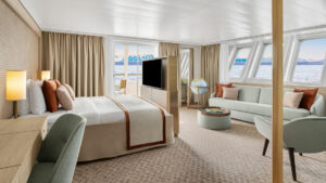 A large room with a sliding glass door and a bank of windows looking out on the Antarctic aboard the National Geographic Explorer