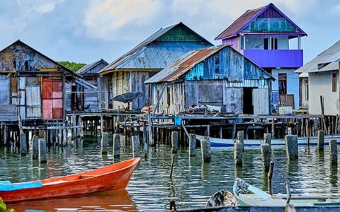 Dilapidated village painted in bright colors and standing on wooden stilts above the water in Indonesia.