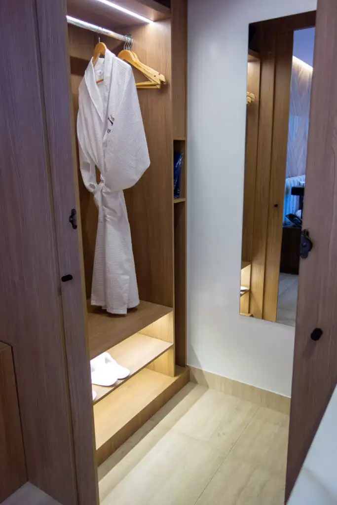 The well-lit closet of the Hermes catamaran's Double Suite showing a robe and slippers