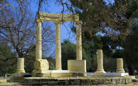 ancient greek columns standing in olympia with trees in the foreground