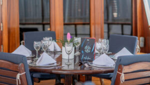 outside seating aboard small cruise ship with set table and white napkins and wine glasses