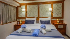 Category P cabin aboard Callisto yacht showing a double bed in the center of the cabin with a window to the right