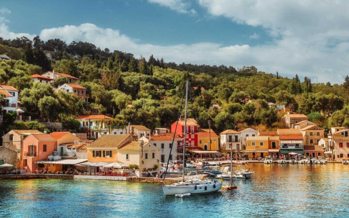 A sunny port scene with homes and yachts seen from the water in Gaios Ithaca Greece.