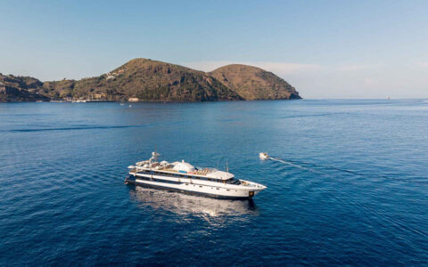 The yacht Harmony G seen from above at anchor among brown hills and blue ocean