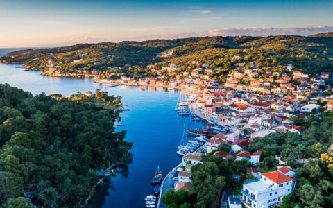 The Greek town of Paxi seen from above showing the harbor, houses on the shore and trees on rolling hills