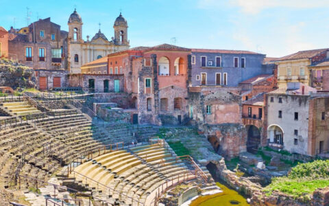 Catania, Sicily's stone amphitheater leading to a grassy stage surrounded by colorful buildings, seen on cruises to Malta.