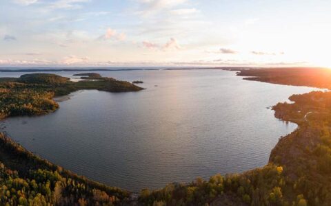Aerial view of a calm inlet on Lake Huron at dusk with fall colors under clouds, seen on small ship great lakes cruises.