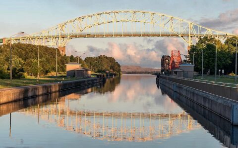 Yellow draw bridge over glassy canal at sunset in Saul St. Marie, Ontario, Canada, seen on small ship greast lakes cruises.
