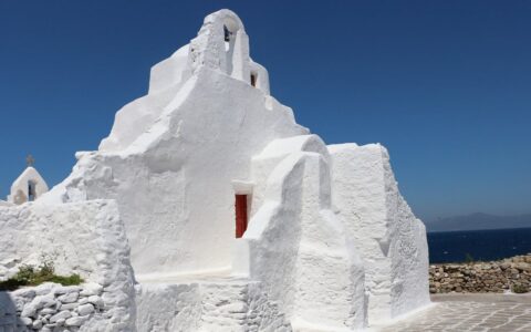 A traditional white-walled chapel seen from the exterior on a blue-sky sunny day