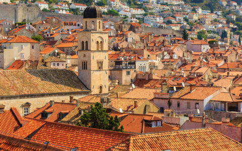 Aerial view of terracotta roofs & a belltower along the hilly old-world city of Dubrovnik, Croatia.