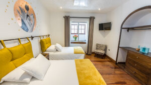 Superior room with 2 single beds in white linens with gold accents, wood floor, small window & dresser plus gold leaf wall art.