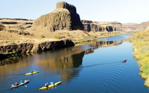 Columbia & Snake Rivers Journey small ship cruise passengers kayaking on calm waters in a sunny pacific northwest gorge