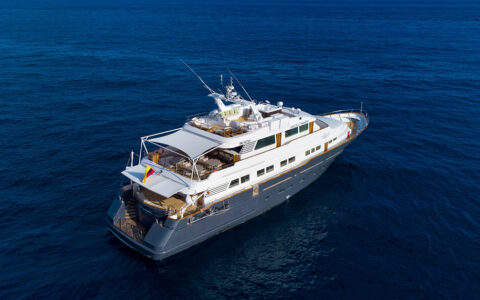 Aerial photo of the blue and white Galapagos Angel yacht sailing over deep blue water
