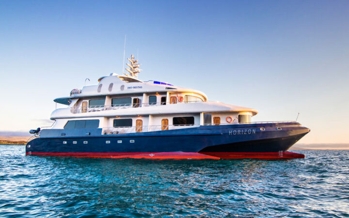 The exterior of the Galapagos Horizon trimaran ship during sunset as it sits at anchor