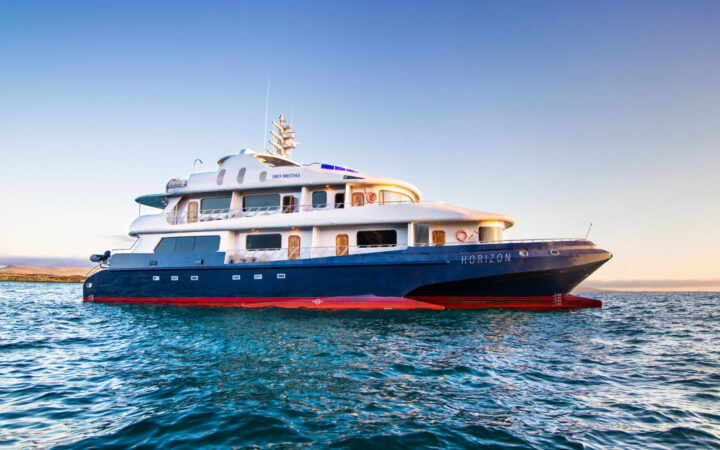The exterior of the Galapagos Horizon trimaran ship during sunset as it sits at anchor