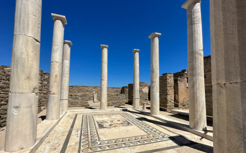 Beige Greco-Roman stone columns surround an open-air pavilion with marble patterns inlaid, seen on a Greece and Turkey cruise.