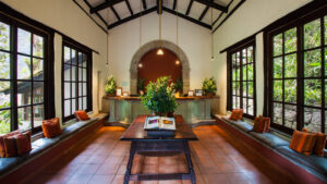 Front desk, for small machu picchu hotel with large windows on both sides , window benches, and greenery to set the mood