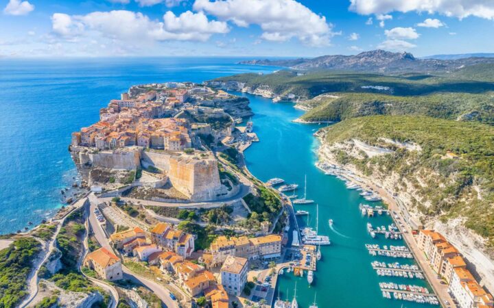 Ariel view of the breathtaking Bay of Corsica with small sail boats and ships parked next to ancient stone buildings and red toned roofs