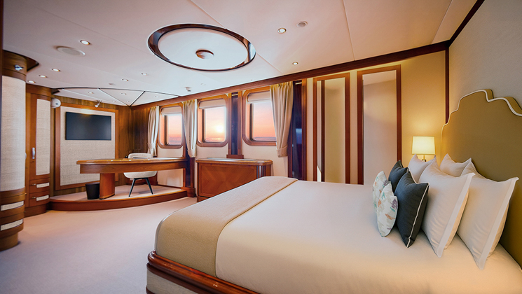 Suite #301 on Aqua Lares Africa superyacht with double bed, beige & wood accents, view windows, desk on riser & soft lights.