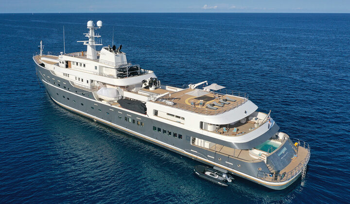 Aerial view of port side of gray Aqua Lares yacht at sea, with 6 guest decks, Jacuzzi, swim step, heli deck loungers & Zodiac.
