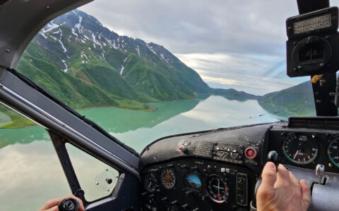 View out the front of an aircraft on a cloudy day in Alaska flying over glassy waters