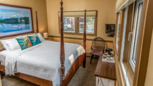 king bed in a hotel room with a large wooden bed with white sheets.