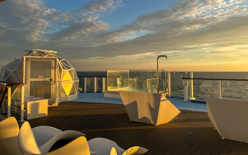 Outdoor space for guests on National Geographic Endurance, featuring outdoor igloo and hot tub, as the sun sets over the Iceland seas