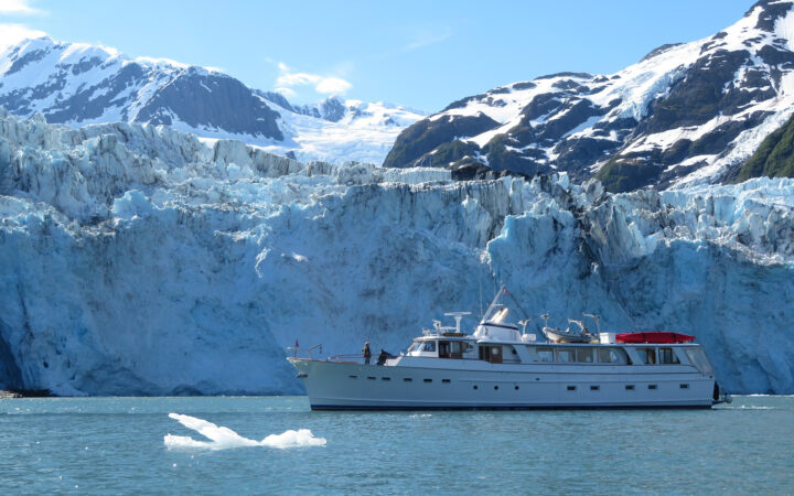 Family yacht charter cruises before a towering glacier in Prince William Sound, Alaska.