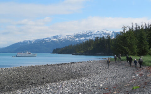 Travelers hike a rocky shore near the Sea Star yacht in Kenai Fjords National Park.