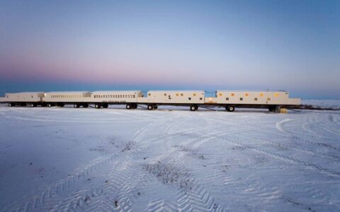 The Tundra Lodge at dusk with a snowy ground and pink and blue sky