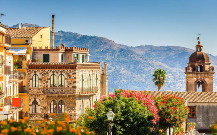 European city with colorful buildings, colorful plants and flowers and rolling hills off in the distance